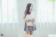 A woman in a school uniform holding a book.