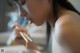 A woman eating noodles with chopsticks in her mouth.