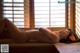 A naked woman laying on a massage table in front of a window.