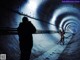 A man taking a picture of a woman in a tunnel.