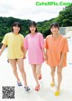 A group of three young women standing next to a swimming pool.