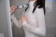 A woman in a white shirt is holding a shower head.